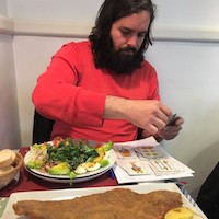 Travel guide Enrique eating and playing card games